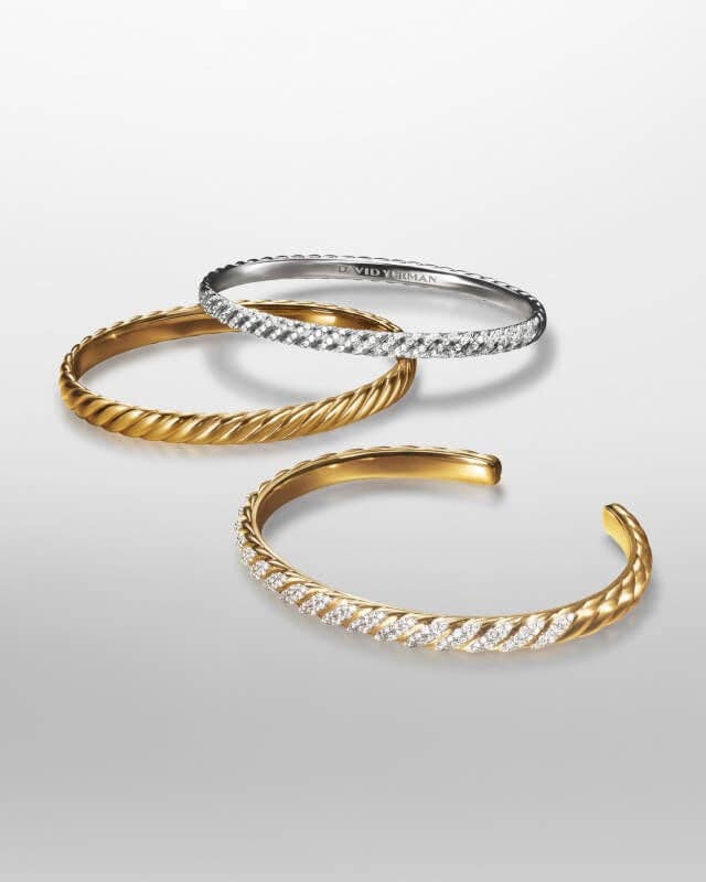 Three David Yurman bracelets in silver and gold.