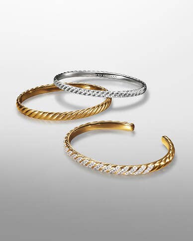 A set of three David Yurman Sculpted Cable Bracelets in gold and silver with and without diamonds.